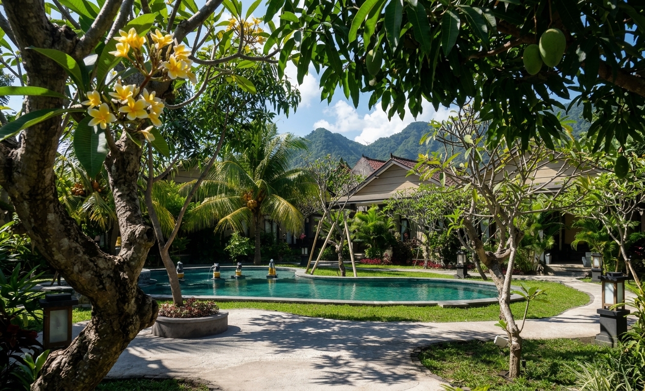 Swimming pool and tropical garden at Doubleyou Homestay Pemuteran with frangipani trees and mountains behind